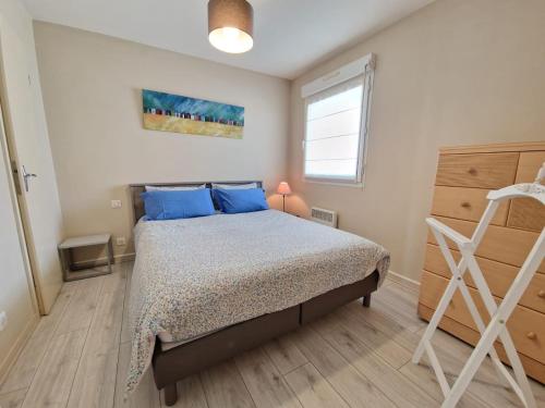 a bedroom with a bed with blue pillows and a window at Appartement avec Piscine, Tennis & Balcon, Centre-ville Chatelaillon-Plage, 6 Pers, 2 Ch - FR-1-706-17 in Châtelaillon-Plage