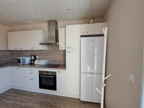  La cuisine est équipée de placards blancs et d'un réfrigérateur. dans l'établissement Beau T3 à Jausiers avec terrasse et parking - FR-1-165A-176, à Jausiers