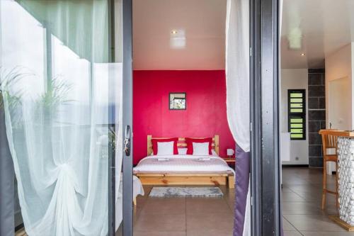 a bedroom with a bed and a red wall at Le Panorama in Cilaos