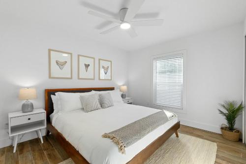 a white bedroom with a bed and a ceiling fan at Duneside Bliss - Steps to the Ocean & Mins to DT in St. Augustine
