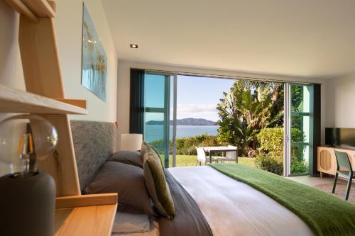 a bedroom with a bed and a large window at Cable Bay Surf Studio in Cable Bay