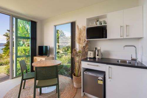 a kitchen with a counter and a table and chairs at Cable Bay Surf Studio in Cable Bay