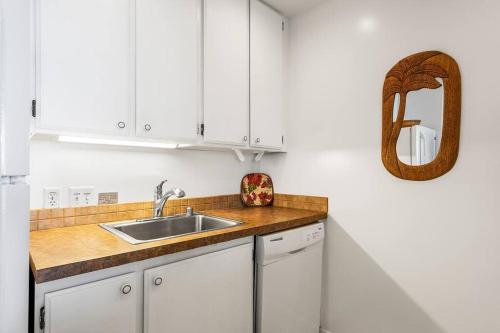 a white kitchen with a sink and a mirror at Dreamy True Oceanfront Condo - Hale Kona Kai 307 by Casago Kona in Kailua-Kona