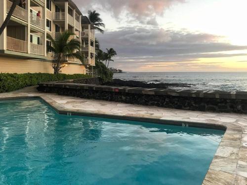 カイルア・コナにあるOceanfront Condo to Enjoy Sea Breeze and Sunset on Lanai which hangs over the ocean!! - Hale Kona Kai 305の建物と海の隣にあるスイミングプール