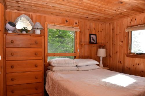 ein Schlafzimmer mit einem Bett, einer Kommode und einem Fenster in der Unterkunft Betty's Place - Cozy ocean front getaway with views of Casco Bay in Orrs Island