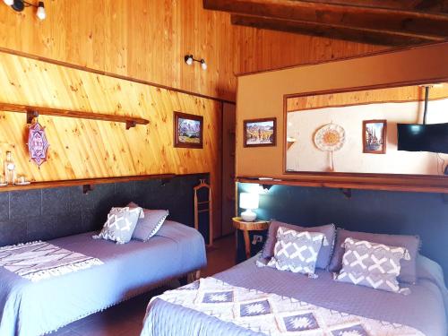 two beds in a room with wooden walls at Alto Ciprés in Salamanca