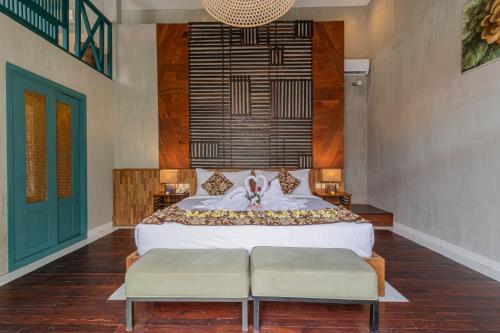 a bedroom with a bed with two benches in it at The Reward Villas Kerobokan in Seminyak