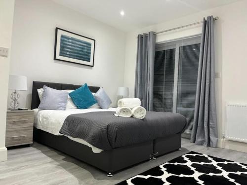 a bedroom with a bed with blue pillows and a window at Watford City Centre Retreat - Spacious Modern Self-Contained Apartment - Sleeps 4 in Watford