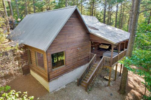 a small cabin in the woods with a porch and stairs at Gorgeous Idyllic Cabin w Hot Tub and Fire Pit Quittin Time is Secluded Romantic Oasis w Luxury Bathroom Double Shower and Bathtub Foosball Table in Broken Bow