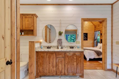 a bathroom with a sink and a bedroom with a bed at Gorgeous Idyllic Cabin w Hot Tub and Fire Pit Quittin Time is Secluded Romantic Oasis w Luxury Bathroom Double Shower and Bathtub Foosball Table in Broken Bow