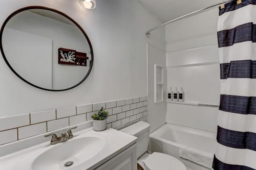 Baño blanco con lavabo y espejo en Wilmington Island Retreat en Savannah