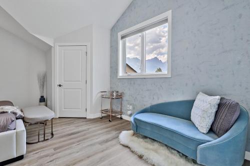 a living room with a blue couch and a window at The Alpine Escape by Samsara Resort Top View Downtown 4BR & 3BTH in Canmore