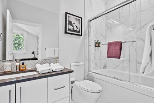 a white bathroom with a toilet and a shower at The Alpine Escape by Samsara Resort Top View Downtown 4BR & 3BTH in Canmore