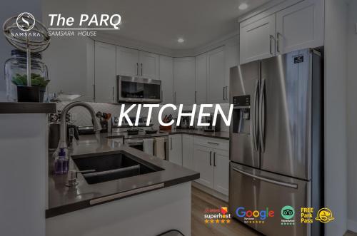 a kitchen with white cabinets and a stainless steel refrigerator at The Parq by Samsara Resort Top View Downtown 4BR & 3BTH in Canmore