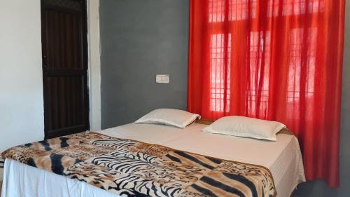 a bed in a room with a window with red curtains at Thrillomania Mcleodganj in Dharamshala