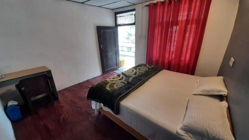 a bedroom with a bed and a red curtain at Thrillomania Mcleodganj in Dharamshala