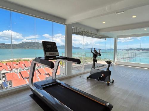 a gym with a treadmill and two exercise bikes in a room with windows at Hillview Cube w/Rooftop Pool in Kuah