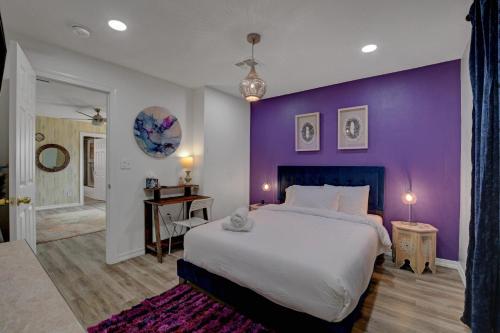 a bedroom with a large bed with a purple wall at Buddha Mansion Luxury Resort - 8BR Modern, HotTub, Huge pool, Sauna, BBQ grill, Game Room in Las Vegas