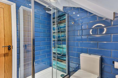 a blue tiled bathroom with a toilet and a shower at Luxury Spacious Pad with Games Room in Sheffield