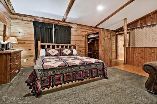 Un dormitorio con una cama en una habitación con paredes de madera. en Secluded 2 story cabin Pool WiFi smart TVs, en Eureka Springs