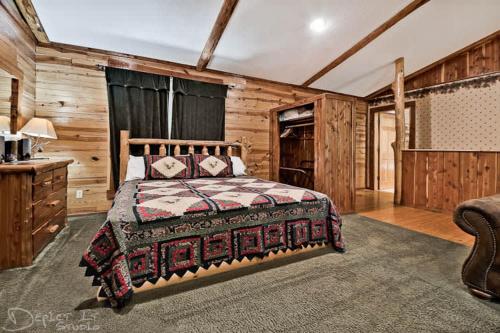 a bedroom with a bed in a room with wooden walls at Secluded 2 story cabin Pool WiFi smart TVs in Eureka Springs