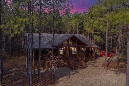 a log cabin in the woods with trees at Large Luxury 2BR Cabin w Hot Tub Double Trouble was designed for fun comfort and memories minutes from buzzling Hochatown and beautiful Beaver Bend State Park in Broken Bow