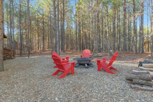 three red chairs and a fire pit in the woods at Large Luxury 2BR Cabin w Hot Tub Double Trouble was designed for fun comfort and memories minutes from buzzling Hochatown and beautiful Beaver Bend State Park in Broken Bow