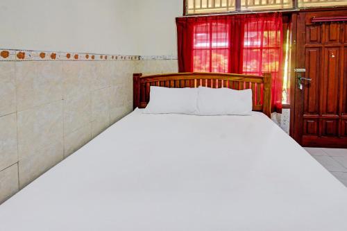 een wit bed in een kamer met een rode deur bij OYO 92560 Astri Homestay in Tjakranegara