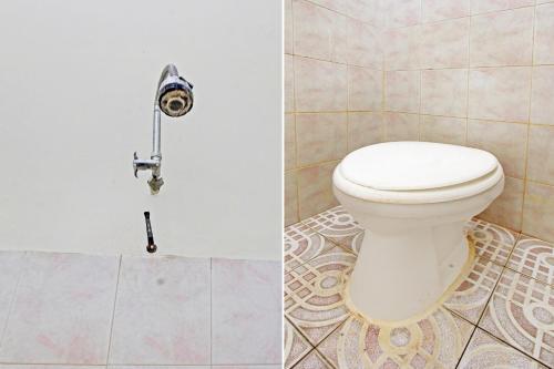 a bathroom with a toilet and a tile floor at OYO 92560 Astri Homestay in Tjakranegara
