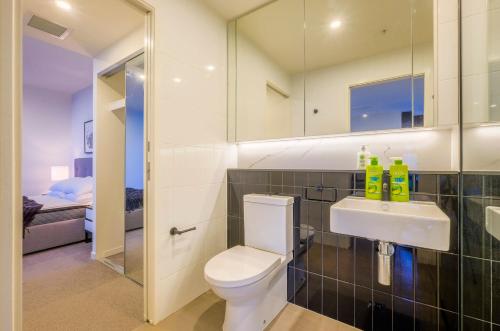 a bathroom with a toilet and a sink and a mirror at Stunning Modern and Central 1BdR Apt at South Bank in Brisbane