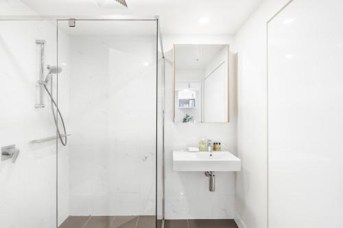 a white bathroom with a sink and a shower at Elegant and Cozy Top Floor 1BD Apartment at South Bank in Brisbane