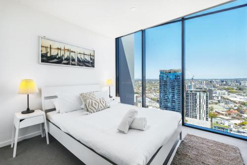 a white bedroom with a bed and a large window at Elegant and Cozy Top Floor 1BD Apartment at South Bank in Brisbane