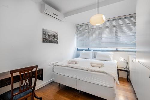 een witte slaapkamer met een bed en een raam bij Amazing 2BR in Gideon by Holiday-rentals in Tel Aviv