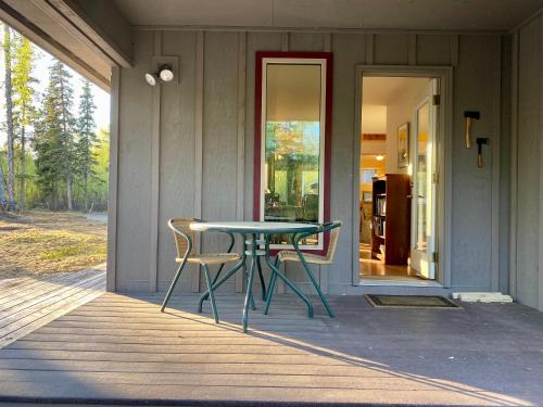 einen Tisch und zwei Stühle auf der Veranda eines Hauses in der Unterkunft Quiet, Elegant & Cozy - 4 Miles from Downtown in Talkeetna
