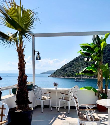 a patio with a table and chairs and the ocean at Liman Hotel Gümüslük - Adult Only in Bodrum City