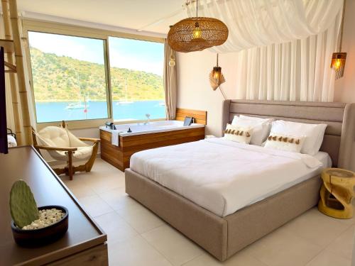 a bedroom with a bed and a tub and a window at Liman Hotel Gümüslük - Adult Only in Bodrum City