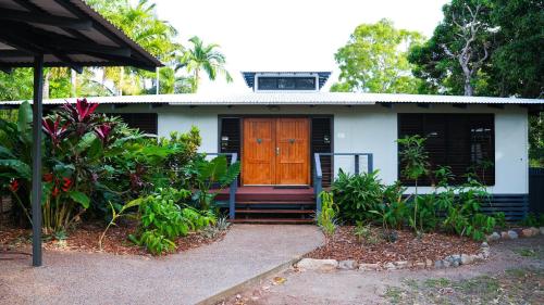 a white house with a brown door and some plants at Picnic House, Luxurious Tropical House in Picnic Bay