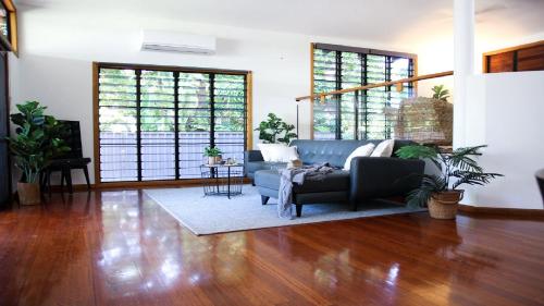 a living room with a blue couch and windows at Picnic House, Luxurious Tropical House in Picnic Bay