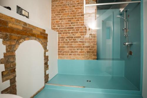 Un baño con ducha azul con pared de ladrillo. en Spacious Apartment in Berlin Mitte for 6, en Berlín