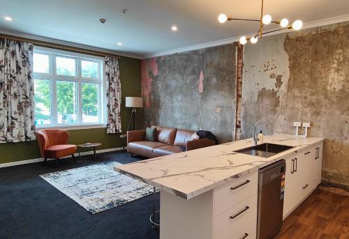 a kitchen and living room with a sink and a couch at Historic Inner City Apartment in Invercargill