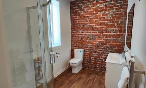 a bathroom with a toilet and a brick wall at Historic Inner City Apartment in Invercargill