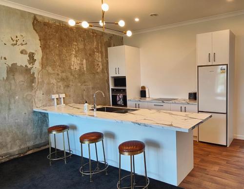 a kitchen with a large island with bar stools at Historic Inner City Apartment in Invercargill