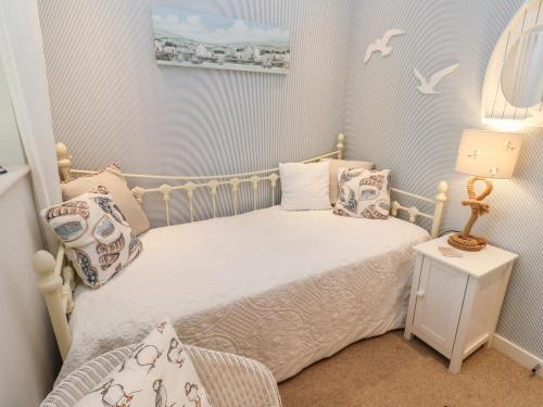 a small bedroom with a white bed with pillows at Number 10 Puffin Cottage in Camelford