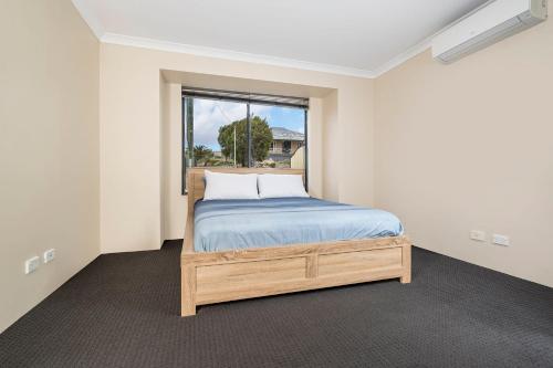 a bedroom with a bed and a window at Spacious 4BR House Right Near The Beach - Fast WIFI and Massive 85' TV in Geraldton