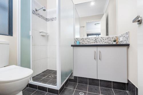 a white bathroom with a toilet and a shower at Spacious 4BR House Right Near The Beach - Fast WIFI and Massive 85' TV in Geraldton