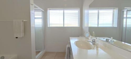 a white bathroom with a sink and a shower at Villa Azure - Sea Views, Pool - 70m onto Robberg 5 Beach in Plettenberg Bay