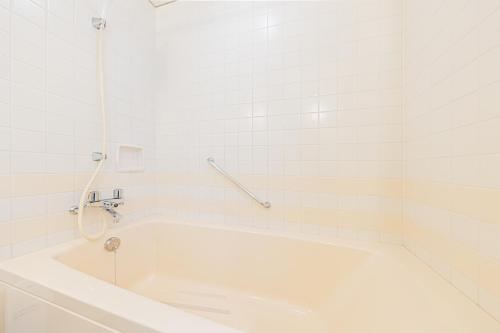 a white bath tub in a white tiled bathroom at Bellevue Garden Hotel Kansai International Airport in Izumi-Sano