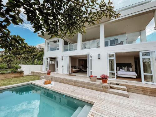 a large house with a swimming pool in front of it at Dizzy Hill Villa with 270° Breathtaking Views. Pool + Patio in Plettenberg Bay