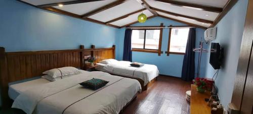 2 camas en una habitación con paredes azules en Zhangjiajie April Hostel en Zhangjiajie