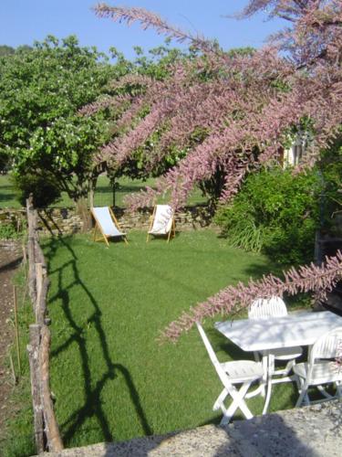 une table et des chaises dans une cour ornée de fleurs roses dans l'établissement La Maison de Juliette, à Les Salelles